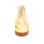 Een witte etherische olieverspreider met geel gemarmerde patronen en een houten basis, geïnspireerd op de marmer goud afwerking van de Tafellamp DORSETTO oplaadbaar 105 uur set van 2, geïsoleerd op een witte achtergrond.