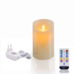 De Oplaadbare LED wax kaars met bewegende vlam D 7,5 X 12,5 CM - warm wit wordt getoond naast een witte adapter en een afstandsbediening met kleurrijke knoppen voor verschillende instellingen.
