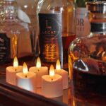 Een close-up van verschillende likeurflessen, waaronder Jack Daniel's en Lecat Cognac, opgesteld op een dienblad met vijf 3D oplaadbare LED-thee/waxinelichtjes 175 uur (met Afstandsbediening, timerfunctie) ervoor gloeiend.
