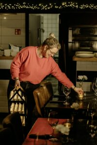 Medewerkster plaatst oplaadbare waxinelichtjes van DORSETTO op een sfeervol gedekte tafel in een restaurant