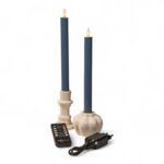 Twee blauwe LED conische kaarsen in witte houders worden afgebeeld met een zwarte afstandsbediening en een voedingsadapter op een witte achtergrond. De kaarsen hebben een realistisch vlameffect.