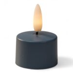 Een klein, rond, donkergekleurd LED waxinelichtje met een plastic vlamvormig topje, aangestoken om op een echte kaars te lijken, tegen een witte achtergrond.