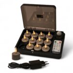 Een set van 12 oplaadbare Charleston Grey oplaadbare waxinelichtjes met een brandtijd tot 400 uur, afstandsbediening, oplaaddoos, één kaars buiten de doos en een zwarte voedingsadapter aan de voorkant.