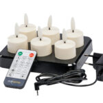 Set aus 6 wiederaufladbaren LED-Teelichtern 3D mit bis zu 400 Stunden Brenndauer, Fernbedienung, Timerfunktion und Ladeschale; alle zusammen auf weißem Hintergrund abgebildet.