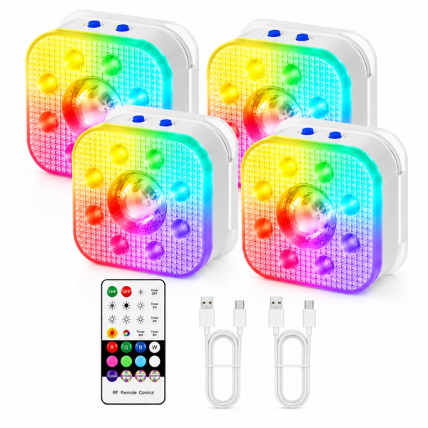 Home 12 Vier vierkante LED puck lampen geven regenboogkleuren weer, elk met een koepel in het midden en knoppen aan de zijkant. Een RF-afstandsbediening en twee USB-oplaadkabels zijn onder de lampjes geplaatst op een witte achtergrond.